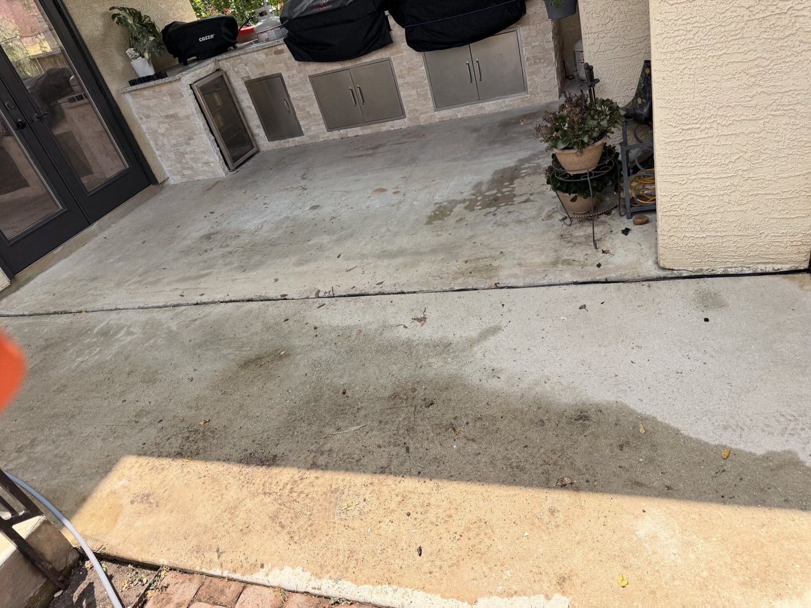 Outdoor kitchen patio before pressure washing, concrete darkened with stains